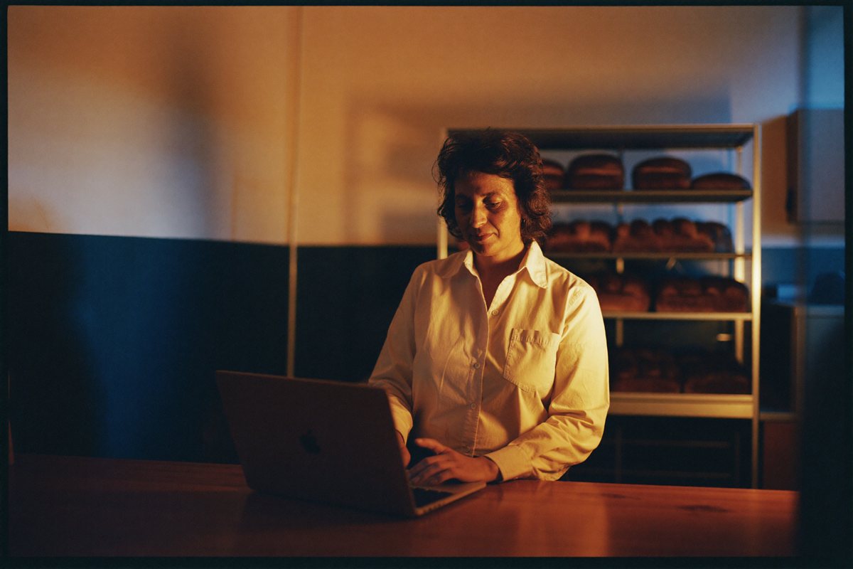 A family bakery owner reviewing her search rankings on a laptop after closing
